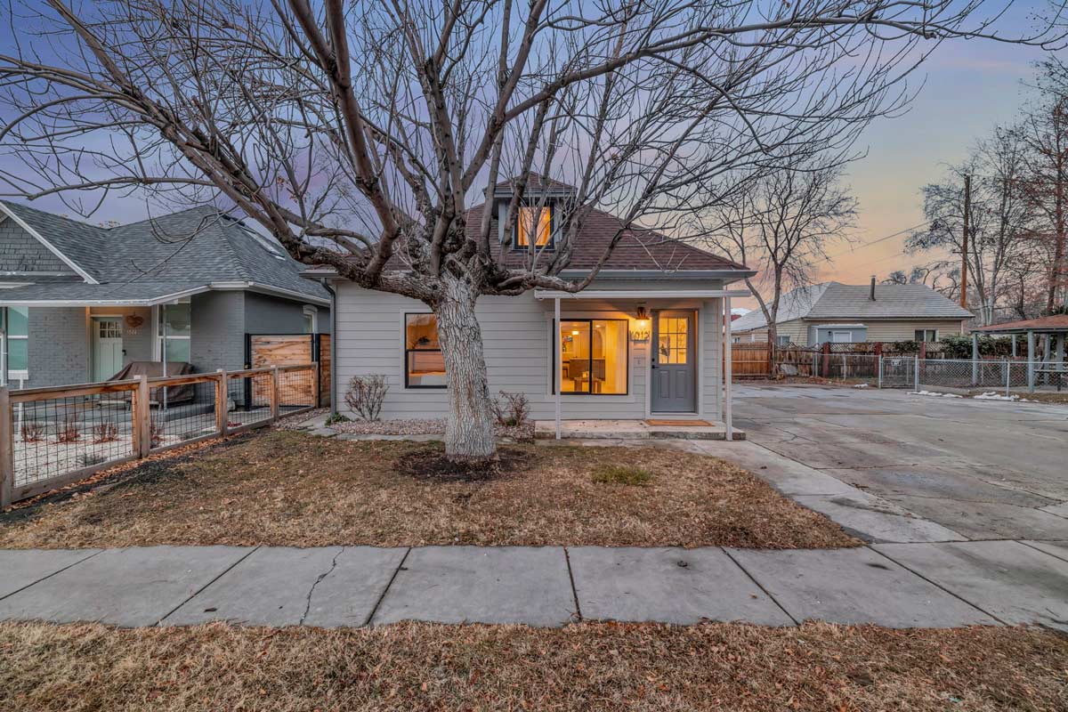 A small house with a tree in the front yard, showcasing a quaint and inviting outdoor space.