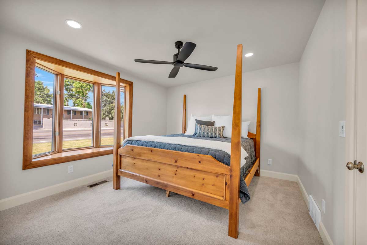 A cozy bedroom featuring a ceiling fan above a neatly made bed, creating a comfortable and inviting atmosphere.