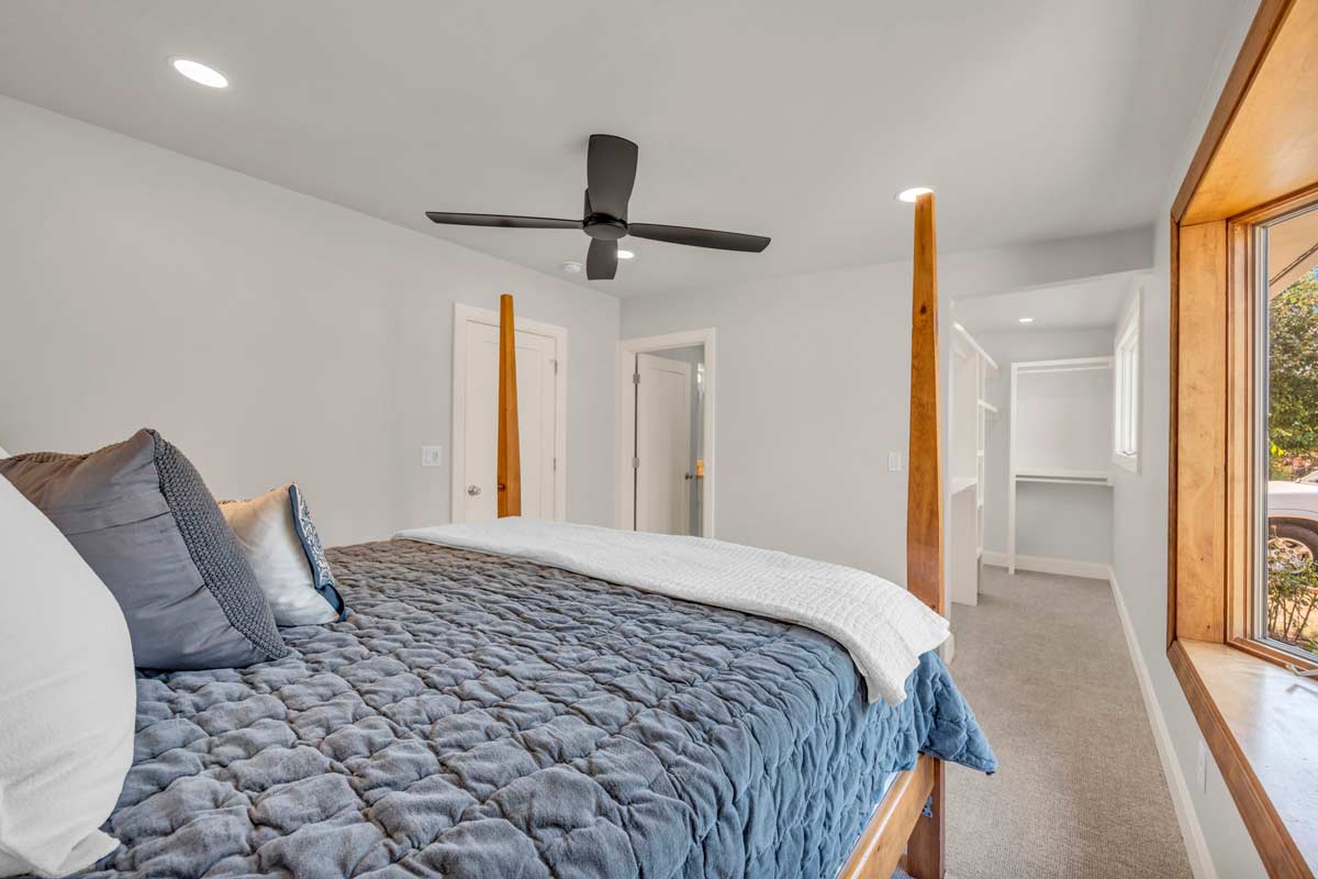 A cozy bedroom featuring a ceiling fan above a neatly made bed, creating a comfortable and inviting atmosphere.