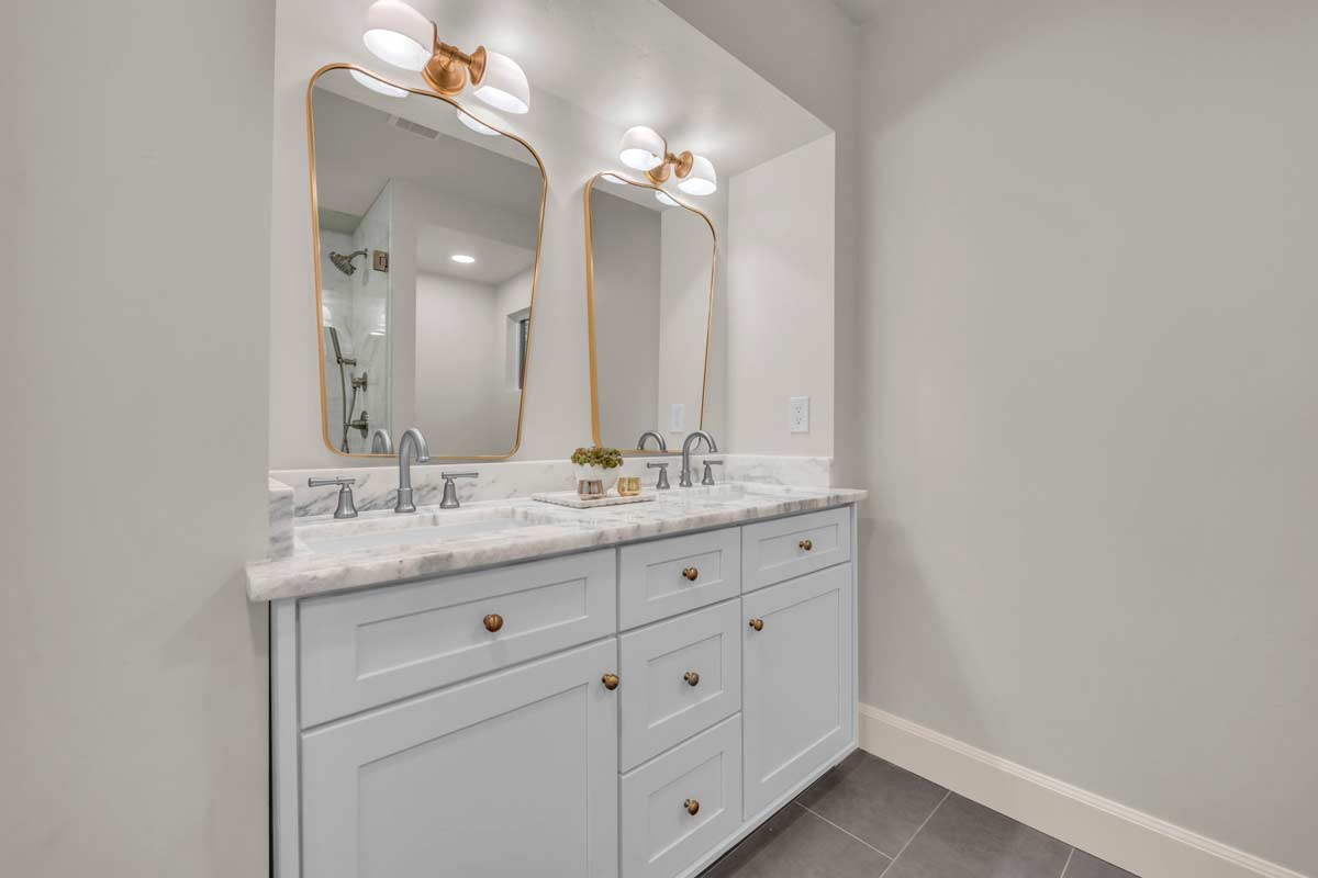 A modern bathroom featuring two sinks and a large mirror above them, showcasing a clean and organized space.