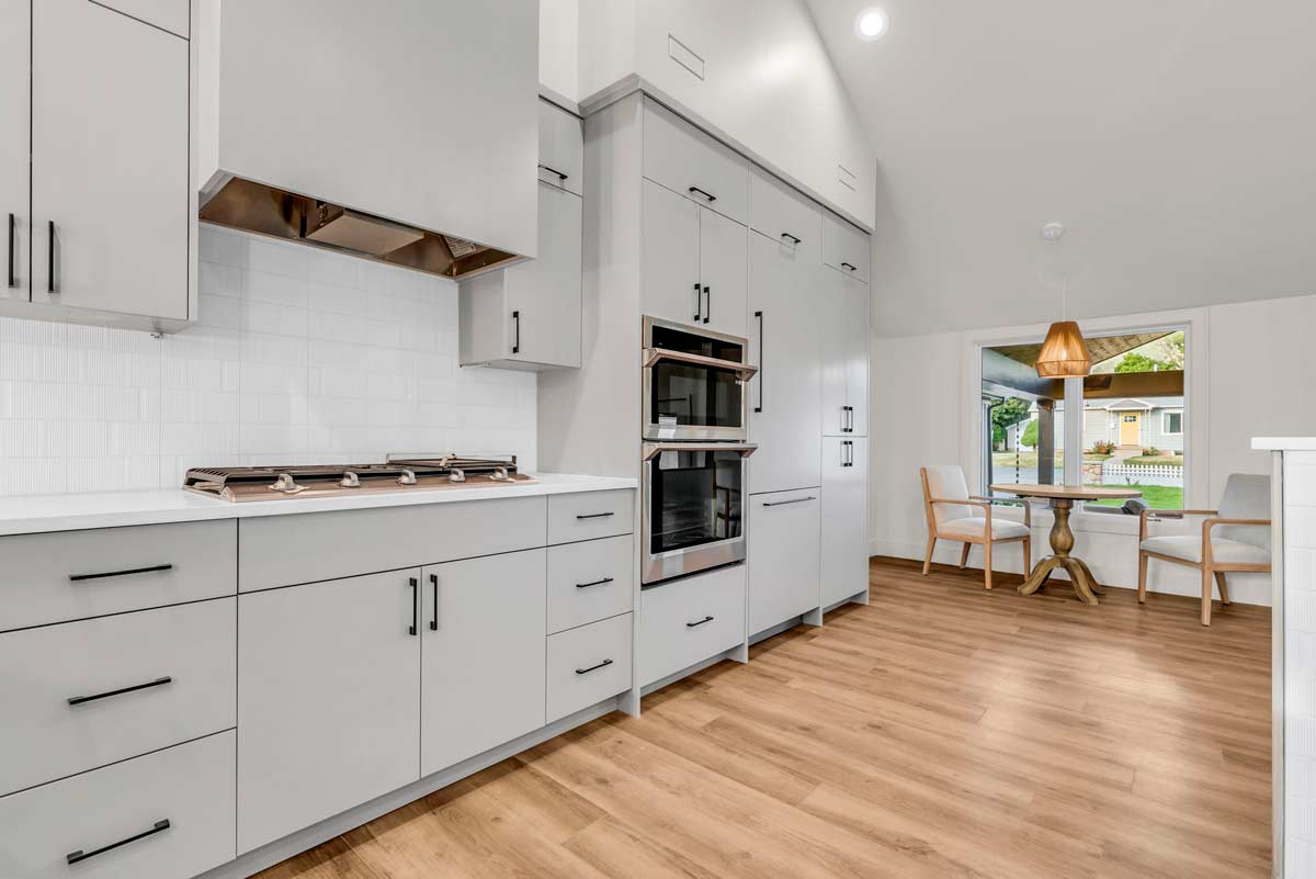 16-3042-millcreek-haven A modern kitchen featuring white cabinets and warm wood floors, creating a bright and inviting atmosphere.