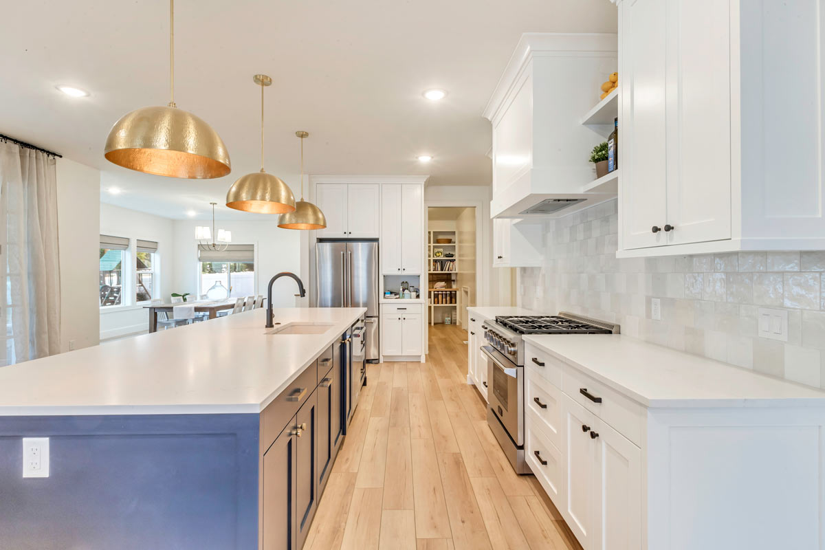 18-baier-residence-new-build A sophisticated kitchen featuring elegant white cabinets and warm wooden floors, exuding a timeless charm and luxury.
