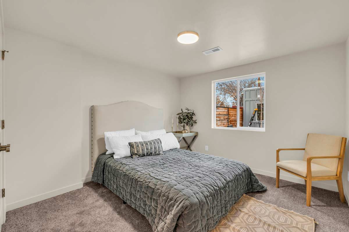 A cozy bedroom featuring a bed, a chair, and a window allowing natural light to enter the space.