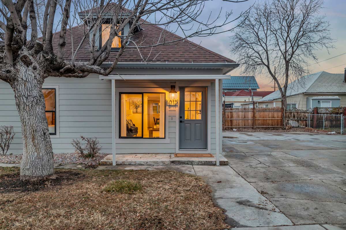 A small house surrounded by a modest yard and a single tree, creating a quaint and inviting atmosphere.