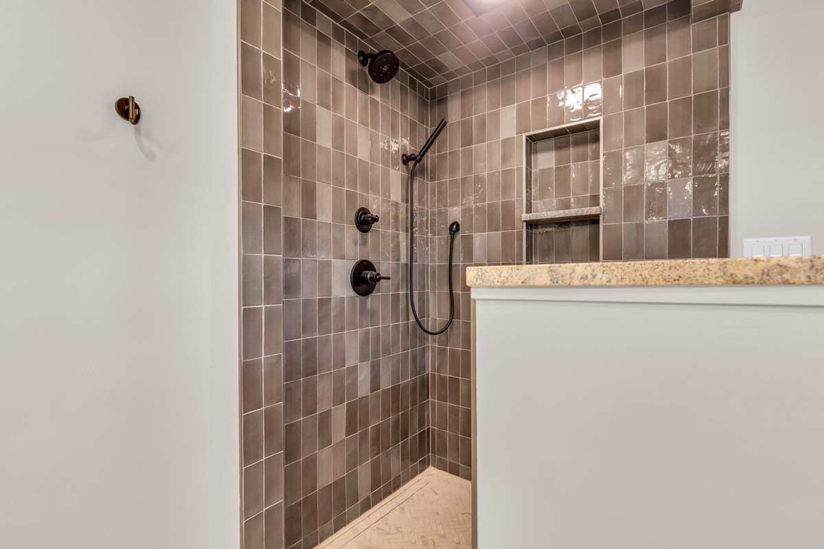 A modern walk-in shower featuring a sleek shower head alongside a compact toilet in a stylish bathroom setting.