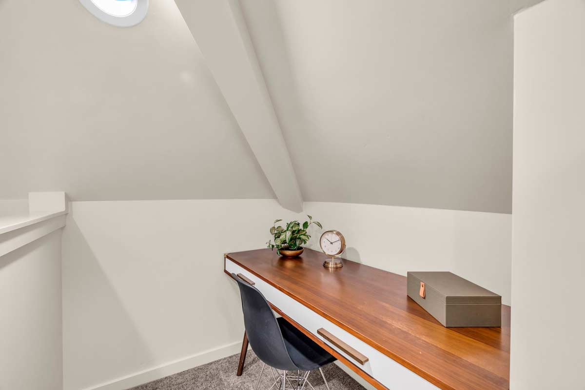 A rustic attic desk positioned near a window, allowing natural light to illuminate the workspace.