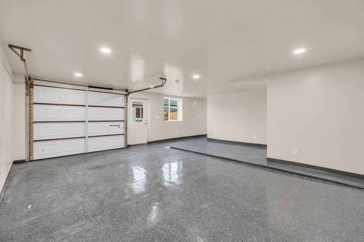 A garage featuring a large main door alongside two smaller white doors.