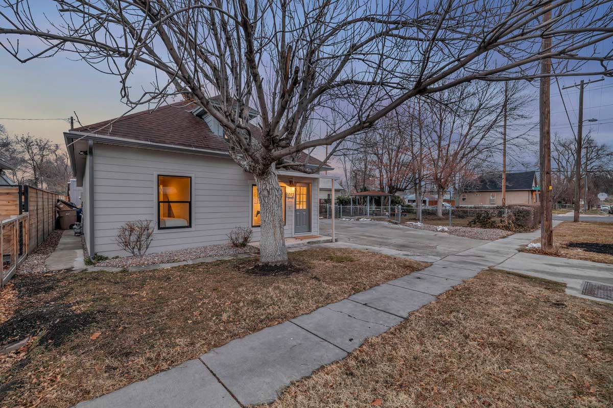A small house surrounded by a lush green yard featuring a prominent tree.