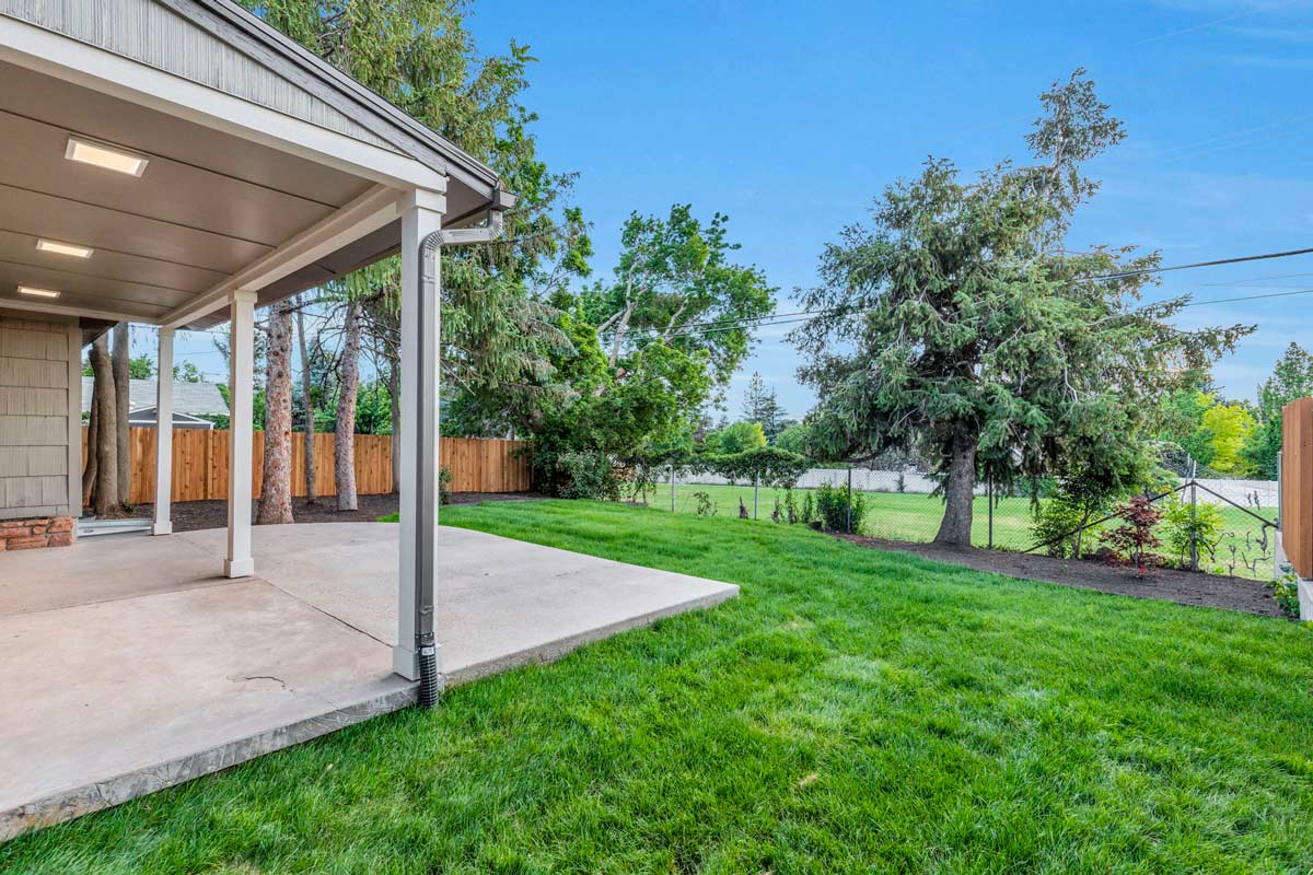 A serene backyard featuring a covered patio and a lush green lawn, perfect for relaxation and outdoor gatherings.