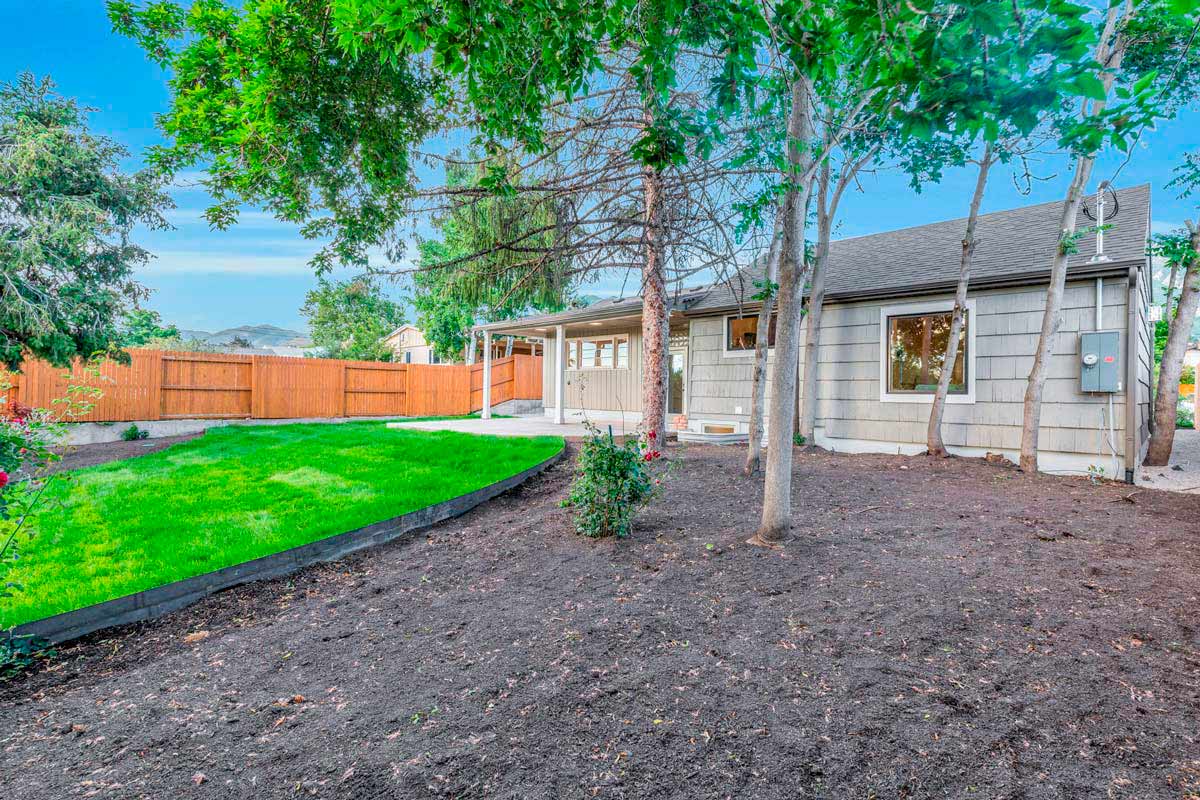A serene backyard featuring a wooden fence surrounded by lush green trees, creating a peaceful outdoor space.