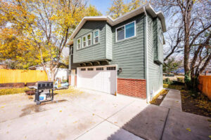 A two-story house with a garage and a barbecue grill outside.