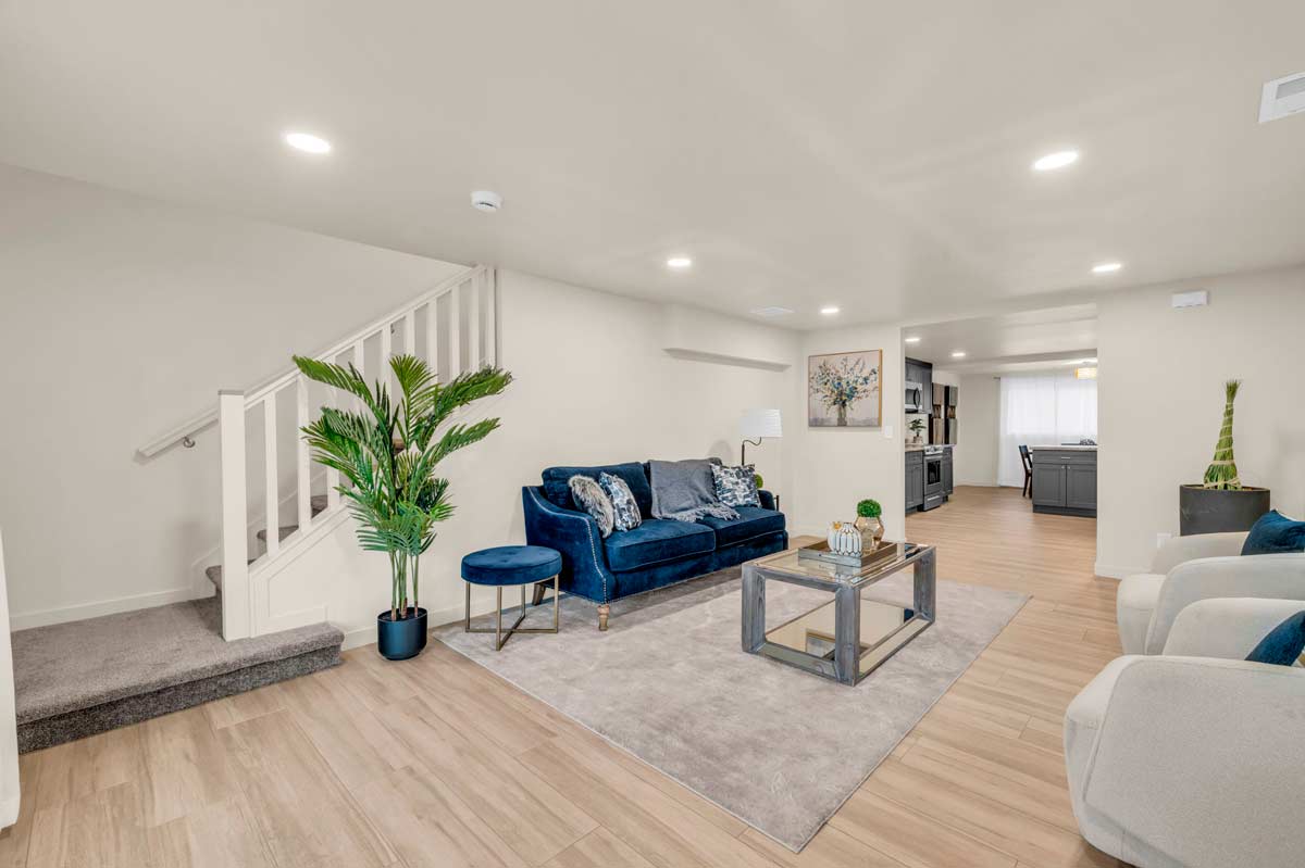 A cozy living room featuring a blue couch and a staircase, creating a welcoming and stylish atmosphere.