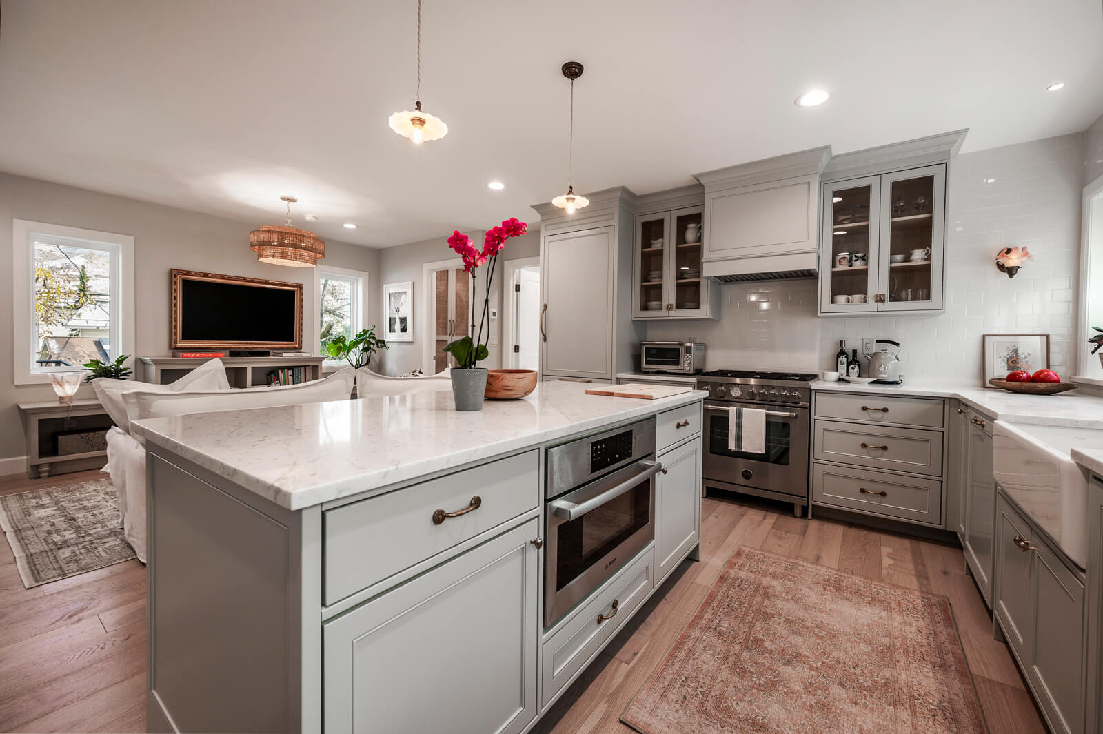 Modern kitchen interior with gray cabinets, white countertops, and pendant lights.
