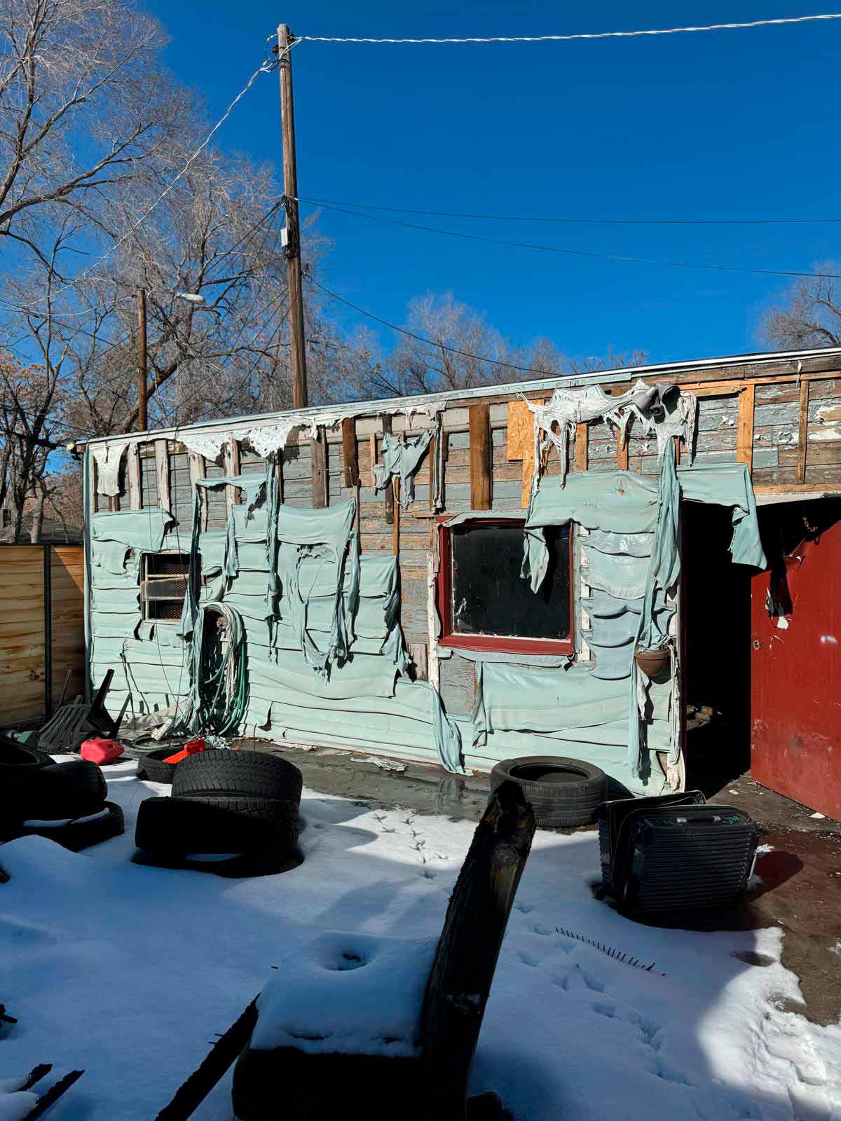A fire-damaged house surrounded by debris, showcasing the aftermath of a devastating blaze.