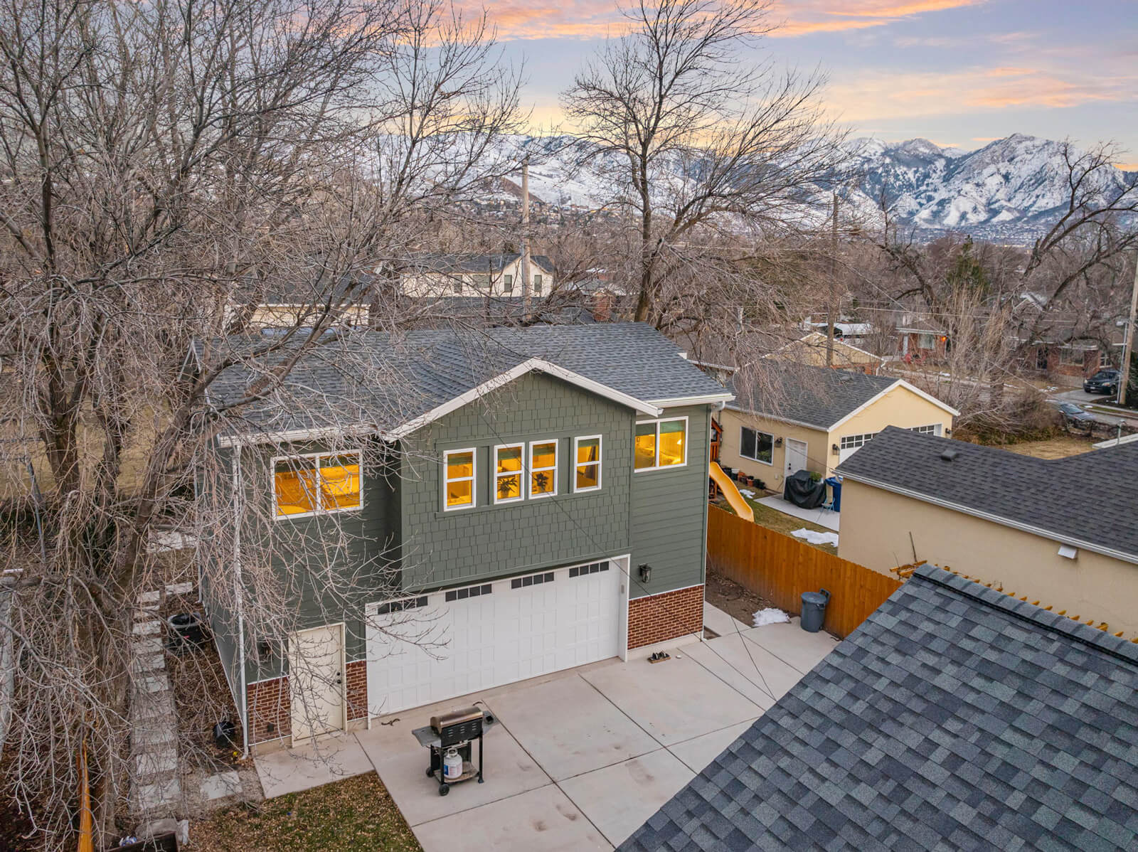 A two-story house with a garage and a barbecue grill outside.