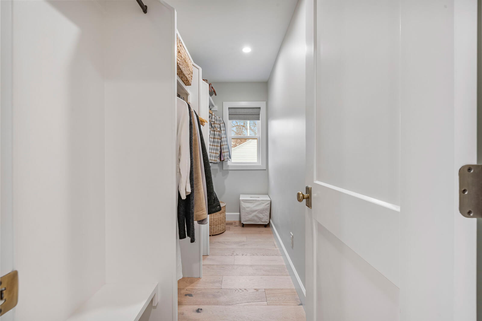 A narrow hallway featuring white walls and polished wooden floors, creating a bright and inviting atmosphere.