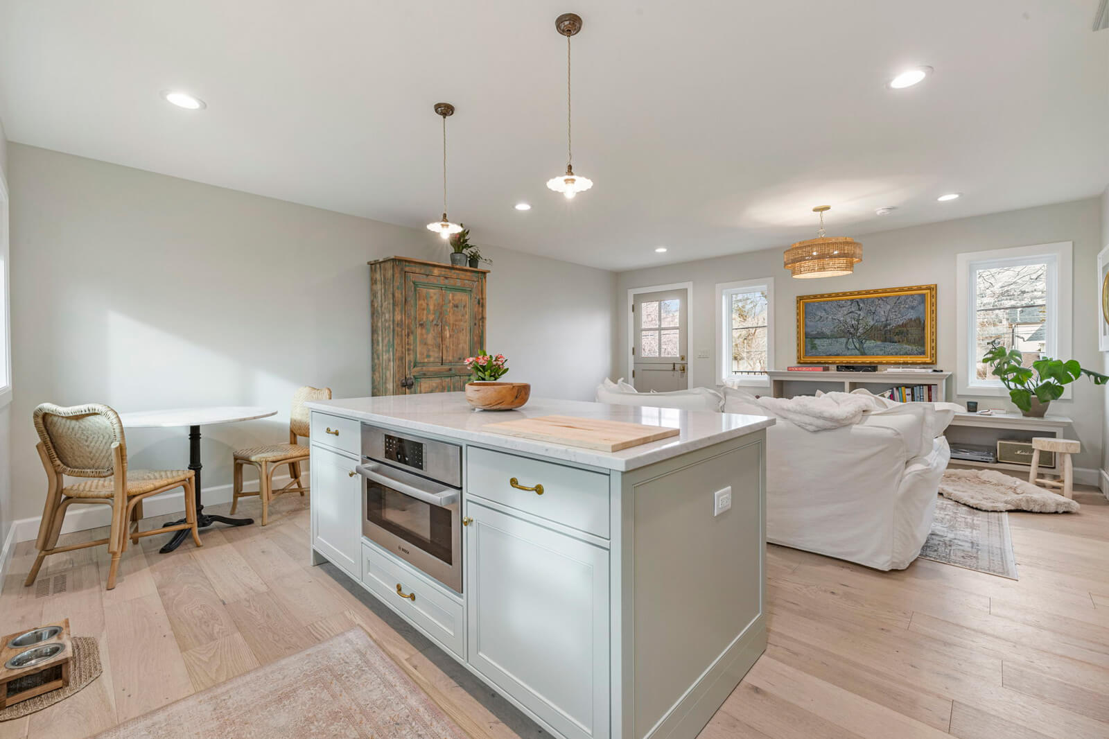 A modern kitchen featuring a white island and elegant wooden floors, creating a warm and inviting atmosphere.