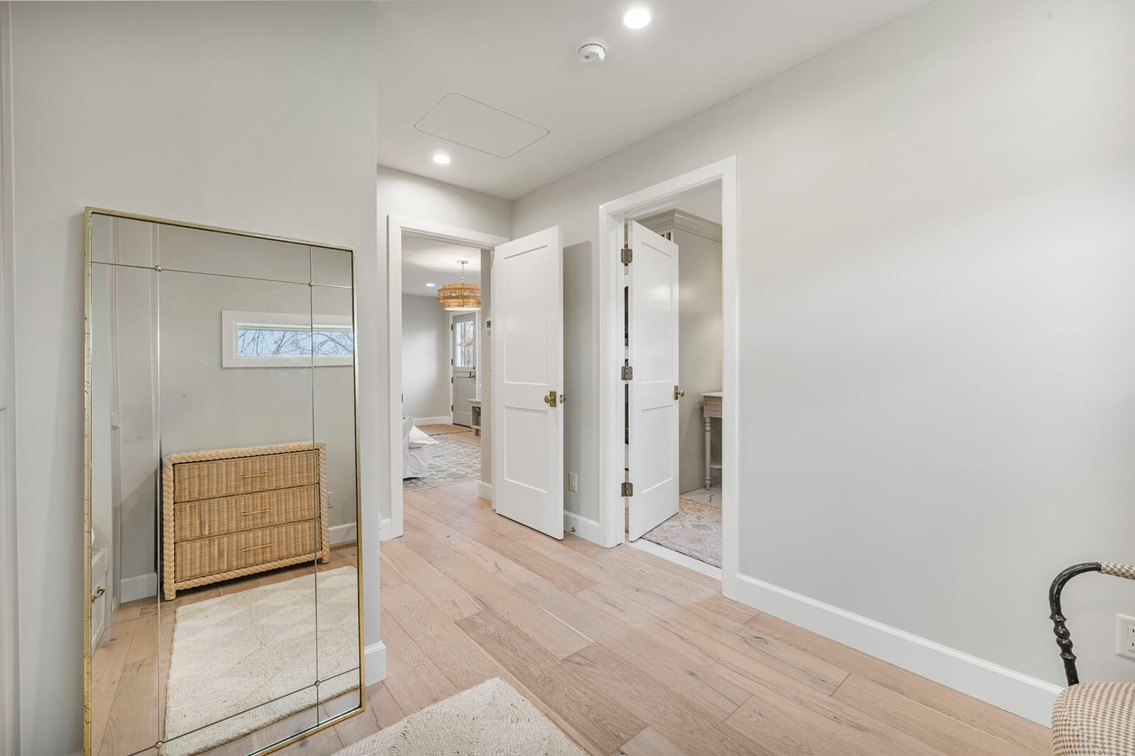A hallway featuring a mirror on the wall and a polished wooden floor, creating a spacious and inviting atmosphere.