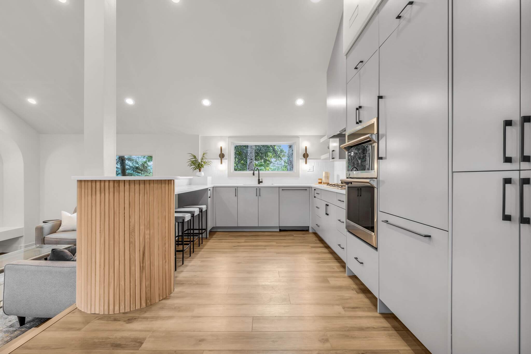 A contemporary kitchen featuring wooden floors and sleek white cabinets, showcasing a clean and stylish design.