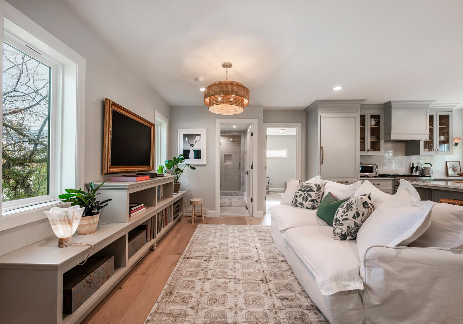 A cozy living room with a white sofa, patterned rug, and wall-mounted TV.