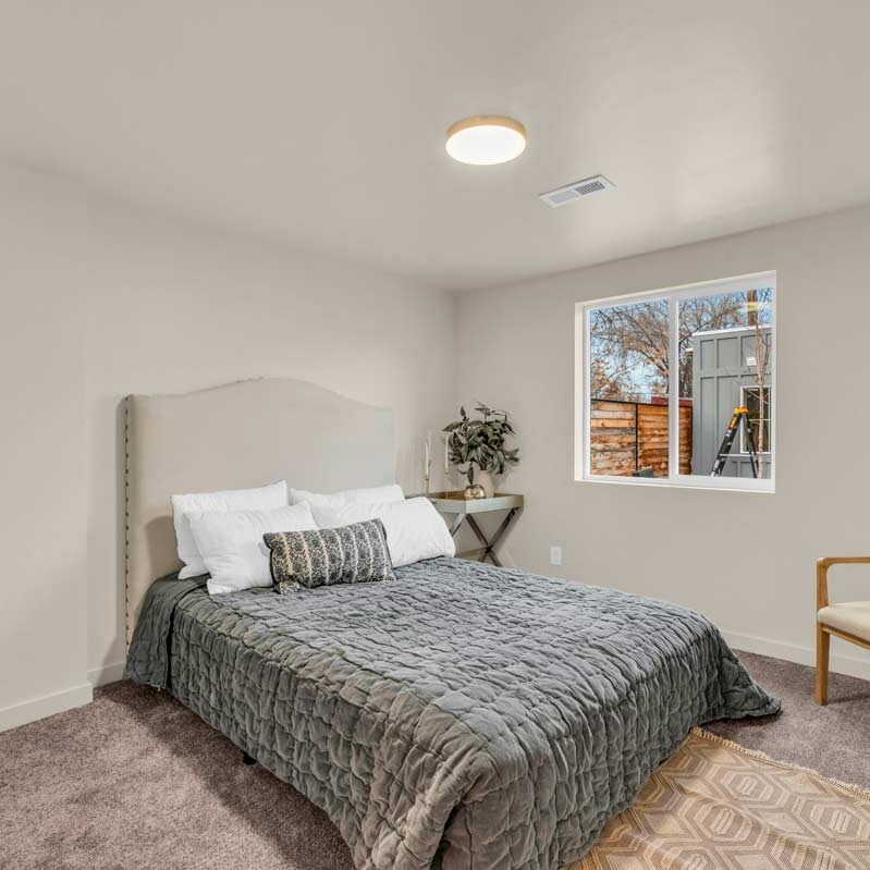 A cozy bedroom featuring a bed, a chair, and a window allowing natural light to enter the space.