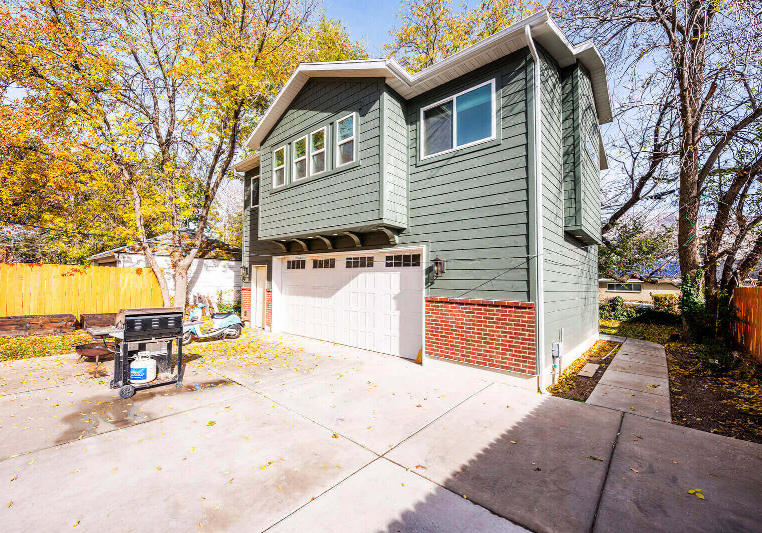 A two-story house with a garage and a barbecue grill outside.