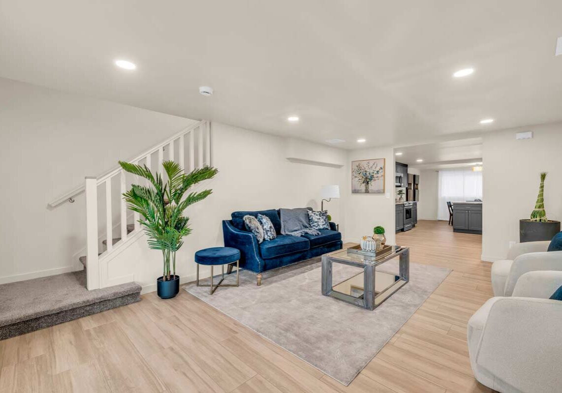 A cozy living room featuring a blue couch and a staircase, creating a welcoming and stylish atmosphere.
